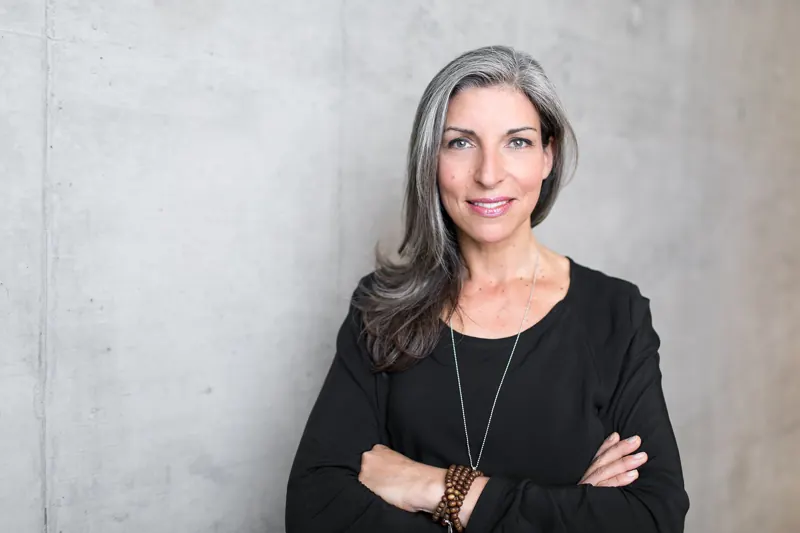 Businessportrait einer Frau mit verschränkten Armen vor Betonwand